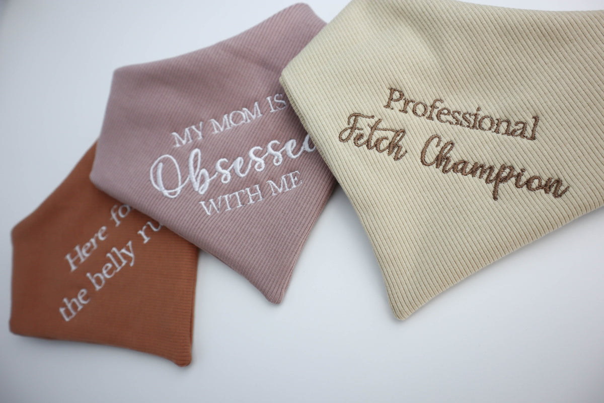 Three dog bandanas with embroidered text on a white background