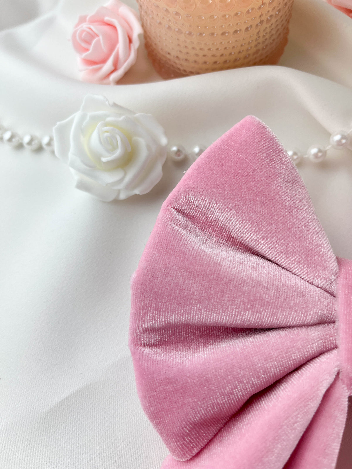 Pink bow with white roses and pearls on a light background