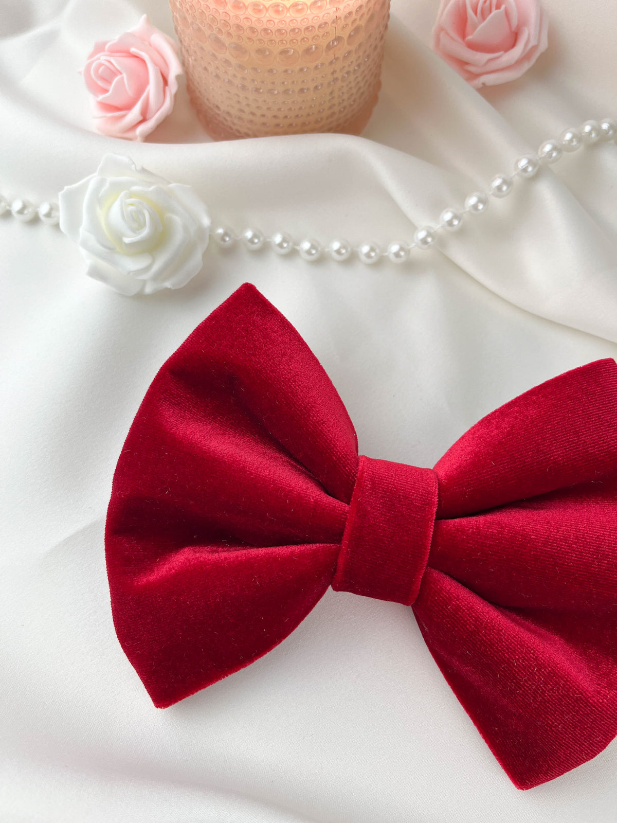 Red bow tie on a white background with flowers and pearls