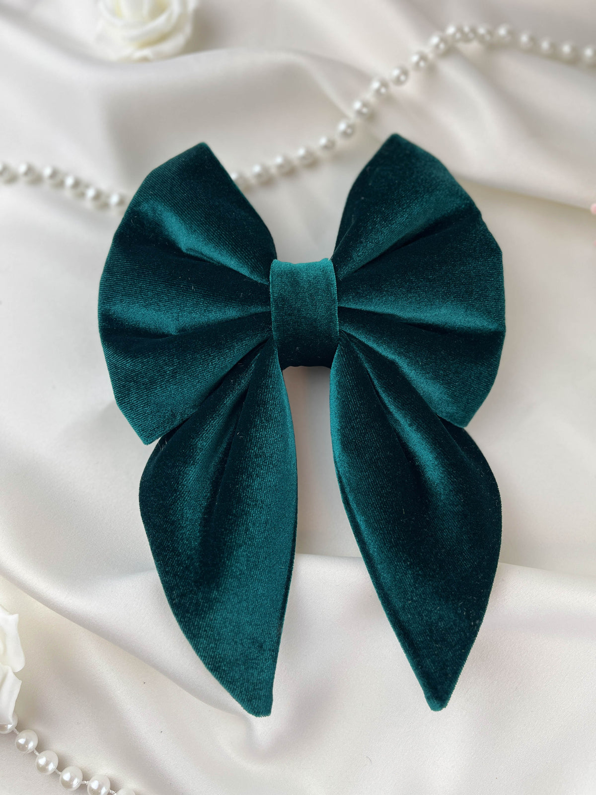 Emerald green velvet bow on a white fabric background