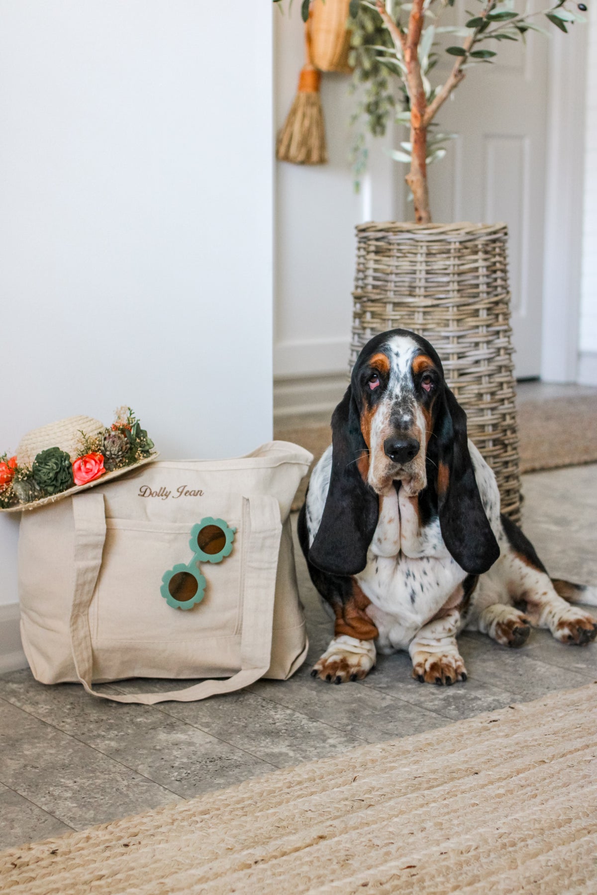 Dog sitting next to a decorative bag with floral arrangements on a wooden floor.