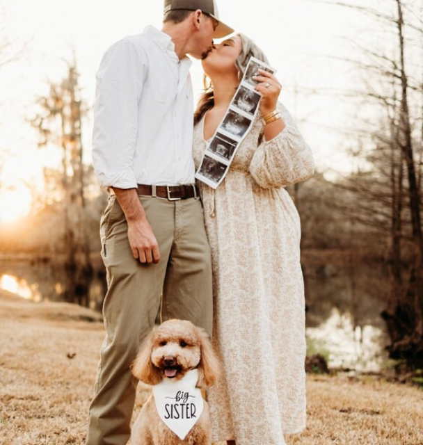 pregnancy announcement Man and woman standing outdoors with a dog, holding ultrasound images.