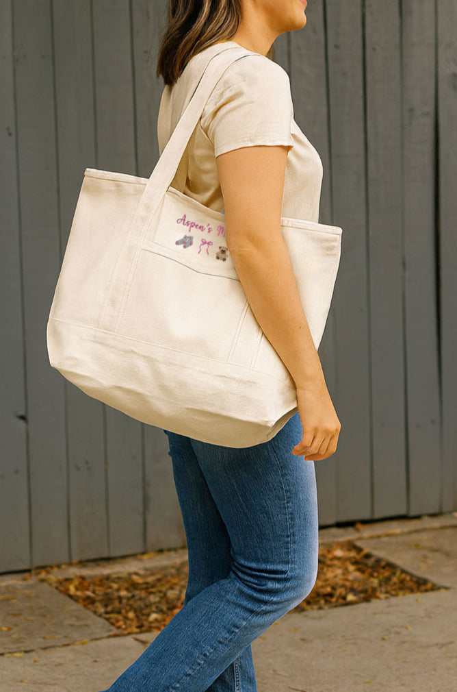 Woman walking outdoors with a beige tote bag that is embroidered