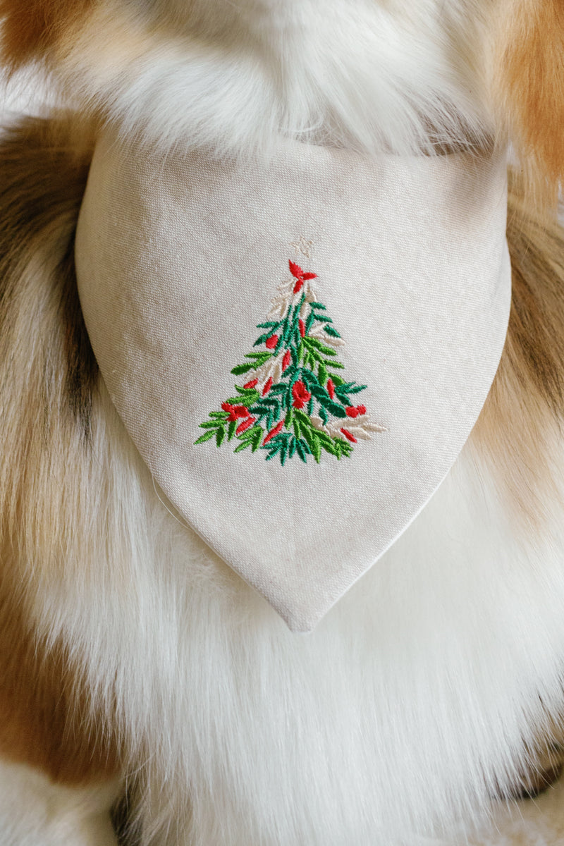 Dog wearing a bandana with a embroidered Christmas tree design on a fluffy fur background