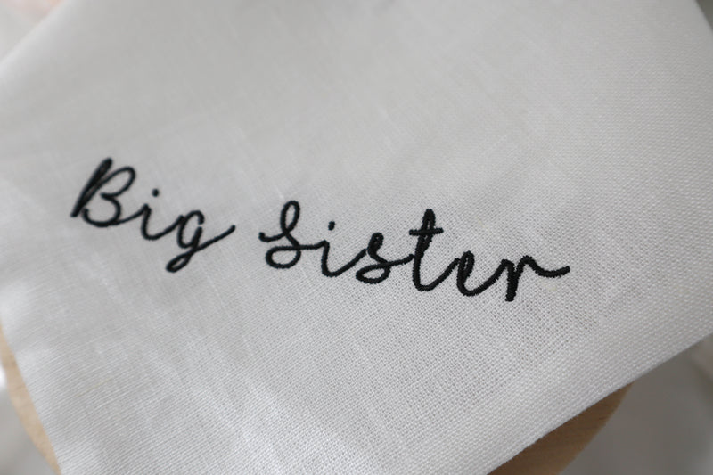 White dog bandana with 'Big Sister' embroidery on a light background
