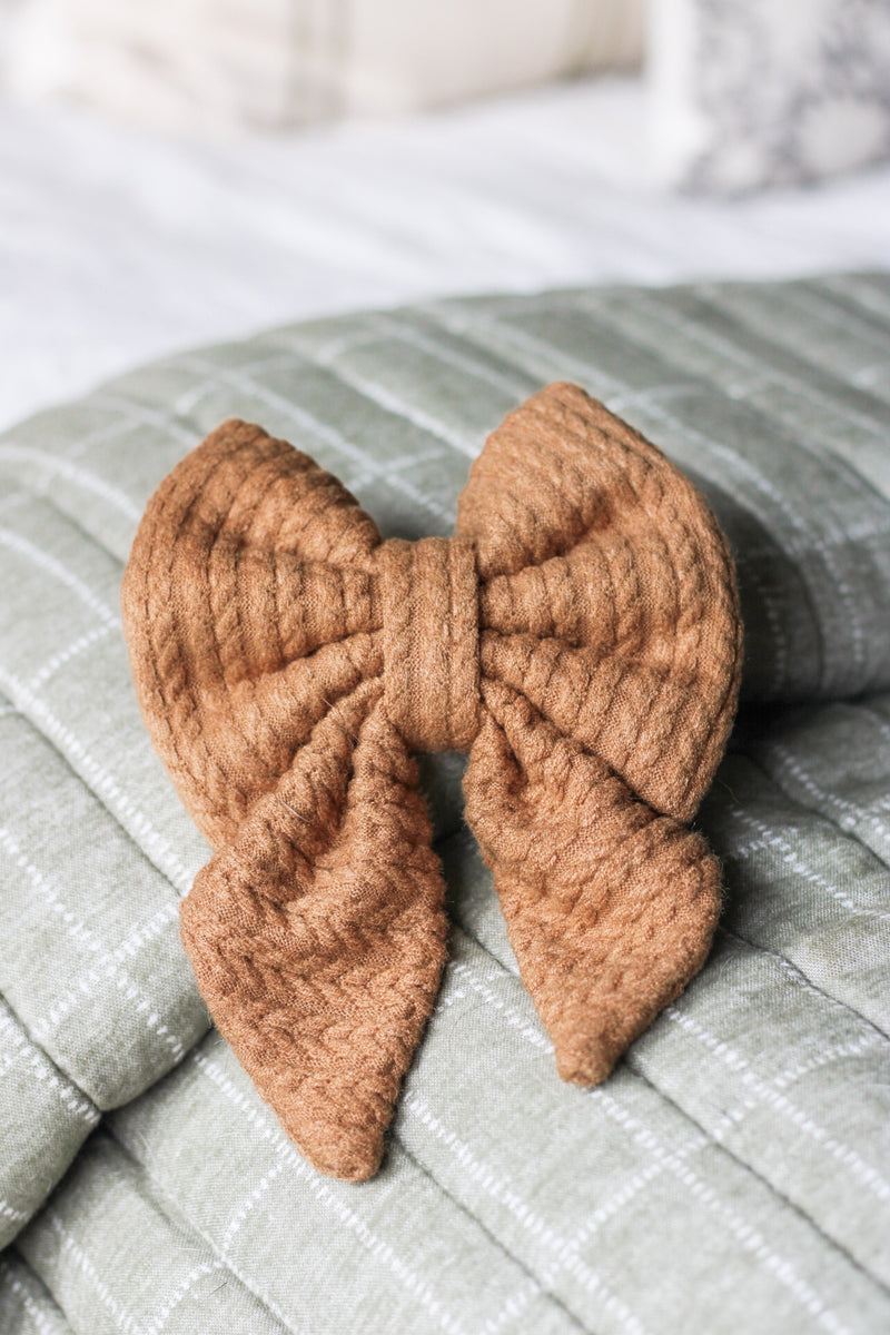 Brown knit sailor bow on a textured surface