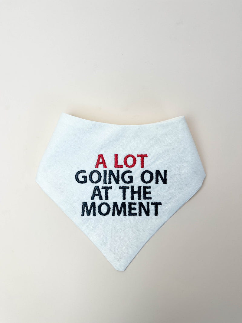 White bandana with text 'A LOT GOING ON AT THE MOMENT' on a beige background