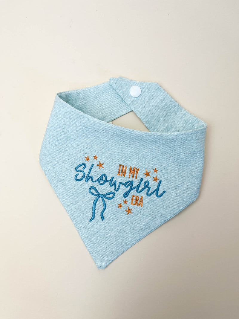 Light blue pet bib with embroidered text on a beige background