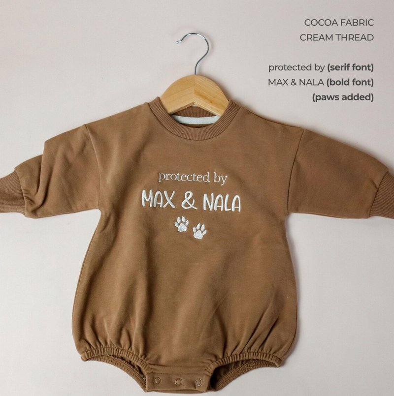 Brown baby romper with 'protected by MAX & NALA' text on a white background