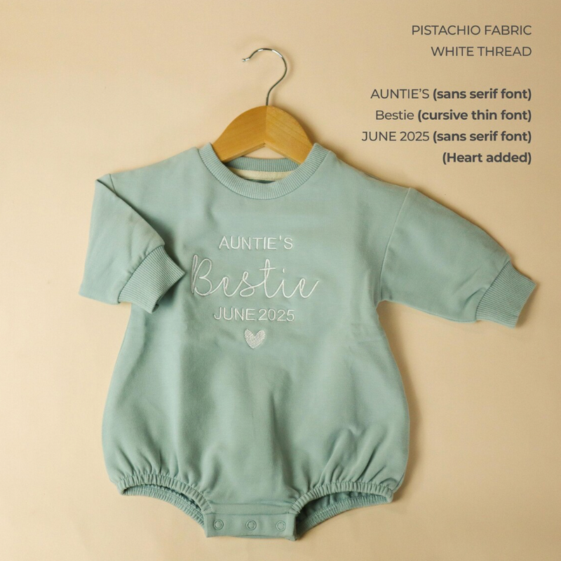 green custom baby romper with text on a beige background
